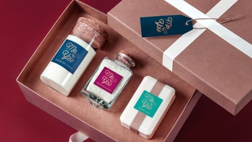 Nyitott ajándékdoboz, amely három "Me & You" márkájú fürdőterméket tartalmaz: illatgyertyát, pezsgőfürdősót és szappant.