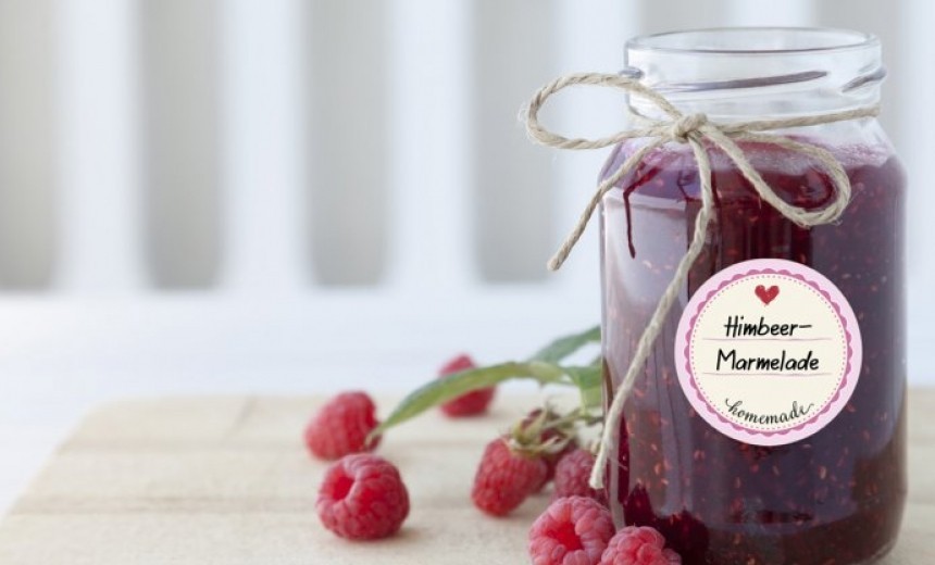Egy üveg málna lekvár, felcímkézve, mellette málna szemek