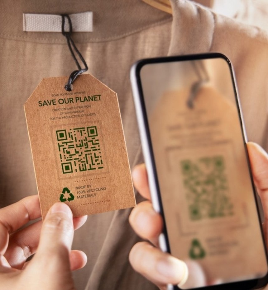 Egy személy okostelefonnal szkennel be egy QR-kódot egy ruhára erősített, környezetbarát címkén. A címkén a "Save our planet" felirat és egy újrahasznosítási szimbólum látható