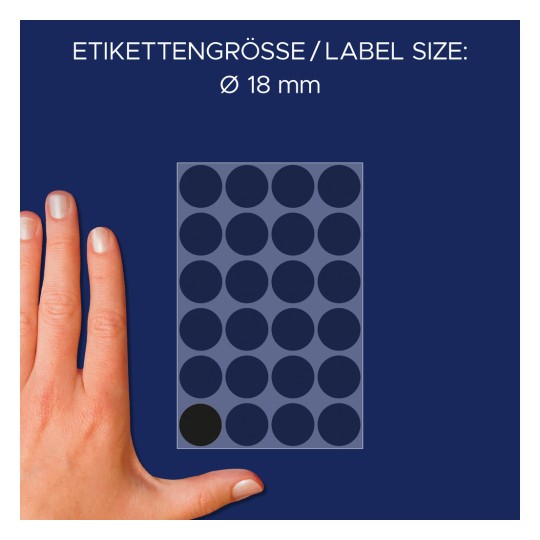 A képen egy kéz látható, amely egy címkelapot tart kör alakú címkékkel, amelyek átmérője 18 mm. A háttér sötétkék, és különböző kör alakú címkék láthatók rácsos elrendezésben, amelyek közül az egyik címke feketének tűnik.