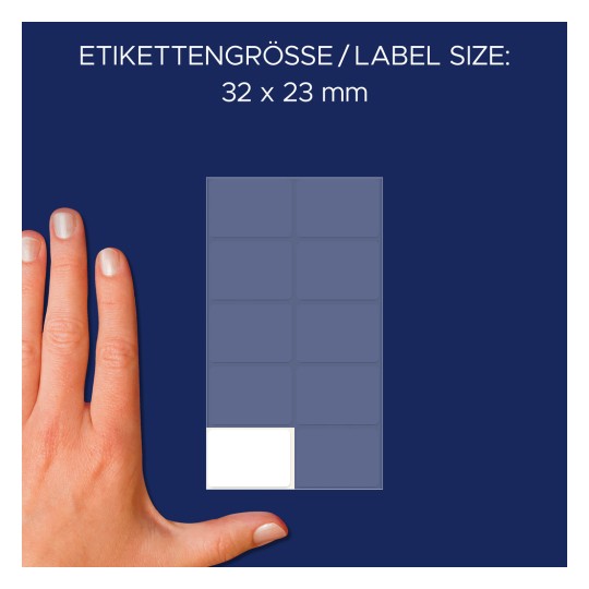 A kép egy kezet mutat egy címkékhez való sablon mellett, amelynek megadott méretei 32 x 23 mm. A háttér sötétkék, és több címkedoboz is látható rajta, amelyek közül az egyik üres.