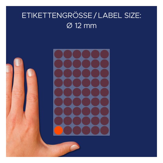 A képen egy kéz látható egy címkelap mellett, ahol a címke mérete 12 mm átmérőjű. A címkék többnyire sötétpirosak, egy narancssárga címke látható.
