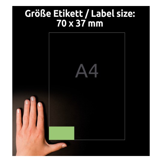 A képen egy kéz látható egy címkeméret-jelző mellett, amely 70 x 37 mm-es méreteket mutat, egy A4-es lap elrendezése mellett. A háttér sötét, kiemelve a címke méreteit.