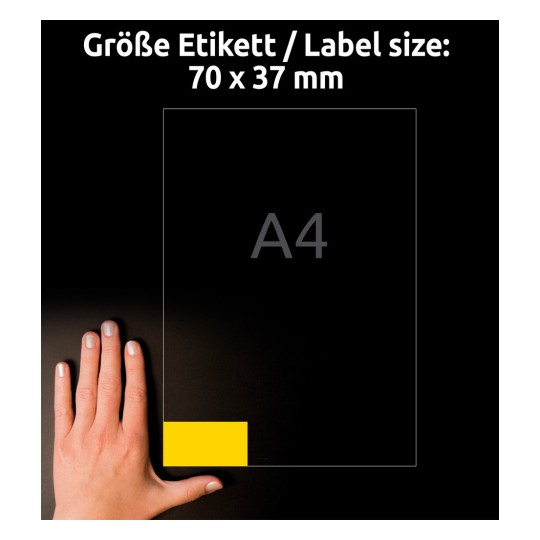 A kép egy kéz mellett egy 70 x 37 mm-es címke méretet jelenít meg, a háttérben egy A4-es papírméret van feltüntetve. A címke sárgával van kiemelve.