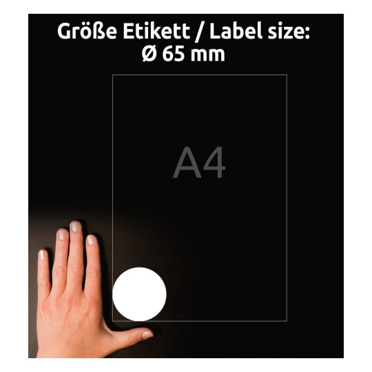 A képen egy kéz látható, amely egy A4-es papír mellett helyezkedik el, és egy fehér kör egy 65 mm átmérőjű címke méretét jelzi, mindez sötét háttér előtt.
