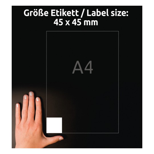 A kép egy kezet mutat egy fekete felületen egy 45 x 45 mm-es címke mellett, a háttérben pedig egy A4-es papírméret látható.