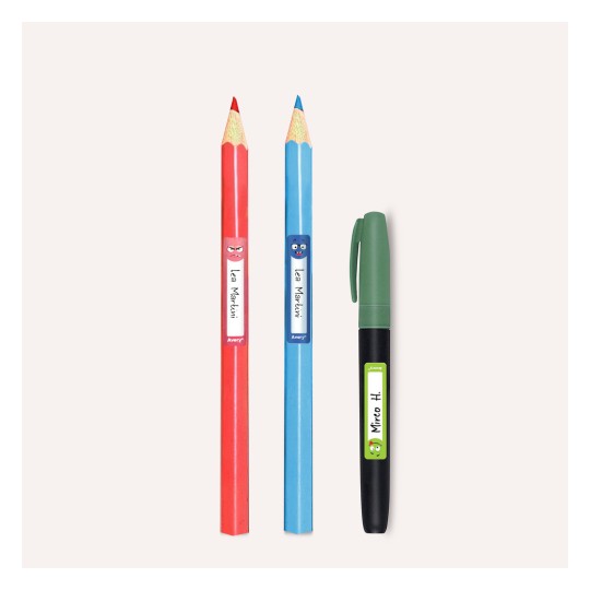 A kép három írószert tartalmaz: egy piros színes ceruzát, egy kék színes ceruzát és egy zöld filctollat. Mindkét színes ceruza játékos karaktercímkékkel van ellátva. A tárgyak világos háttér előtt vannak.