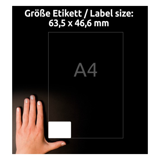 A kép egy kéz mellett egy átlátszó címkét mutat, amelynek méretei 63,5 x 46,6 mm-esek A4 méretű címkékhez, sötét háttér előtt sziluettel.