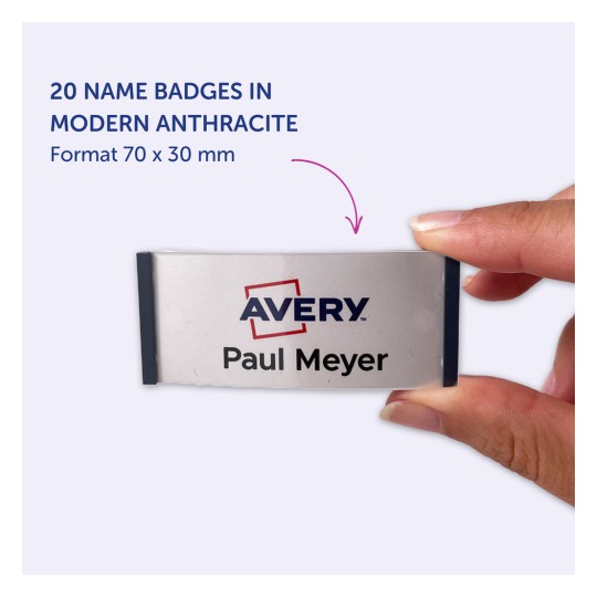 A képen egy kéz látható, amely egy 'Avery' feliratú névtáblát tart 'Paul Meyer' névvel. Ez egy 20 darabos készlet része, modern antracit színben, mérete 70 x 30 mm.