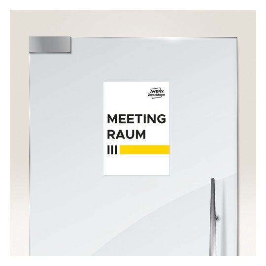 A képen egy ajtótábla látható, amely egy 'MEETING RAUM III' feliratú tárgyalótermet jelöl, alatta sárga csíkkal. A tábla modern, elegáns dizájnt mutat.
