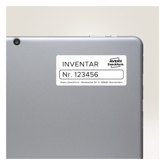 A kép egy tablet vagy laptop hátulját mutatja, amelyen egy címke található. A címkén az 'INVENTAR Nr. 123456' felirat látható, ami a leltári információkra utal, valamint az 'Avery Zweckform' márkanév és egy cím szerepel.