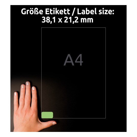 A kép egy kéz mutat, ami egy A4-es papír mellett van elhelyezve, 38,1 x 21,2 mm-es címkével. A háttér sötét, és a címke mérete valamint az A4-es szöveg jól láthatóan ki van emelve.