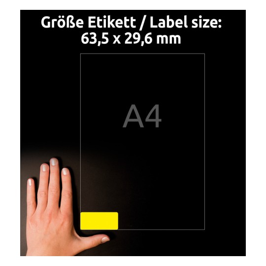 A kép egy kéz látható, amely egy mérettáblázat közelében helyezkedik el, amely 63,5 x 29,6 mm-es méreteket mutat 'A4' megjelöléssel. A háttér sötét, kiemelve a címke és a szöveg láthatóságát.