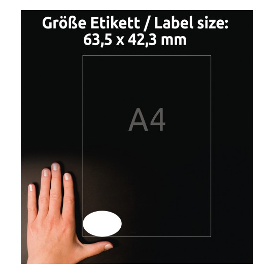 A kép egy kézet mutat, amely egy címke mellett van elhelyezve, amely méreteket jelöl, és a címke mérete 63,5 x 42,3 mm, A4 referencia mellett. A háttér fekete.