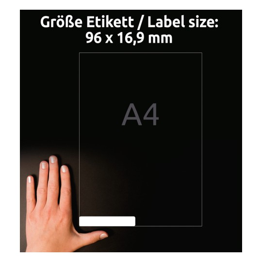 A kép egy kéz mellett egy címkeméret grafikát mutat, amely a méreteket 96 x 16,9 mm-ben jelzi. A címke egy A4-es laphoz viszonyítva van elhelyezve, és sötét háttér előtt jelenik meg.