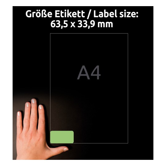 A kép egy kezet ábrázol egy megjelölt terület mellett, amely egy 63,5 x 33,9 mm méretű címkét jelöl egy A4-es lapon. A háttér sötét, és a címketartomány zölddel van kiemelve.