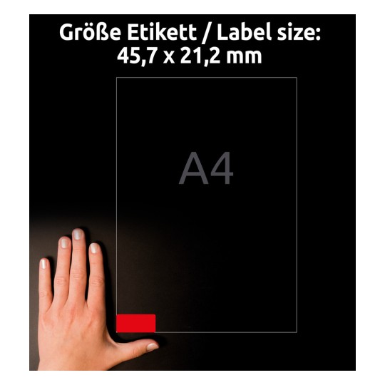 A kép egy 45,7 x 21,2 mm méretű címkét jelenít meg egy kéz mellett, A4-es papírmérettel jelölve. A címke pozíciója egy piros szekcióval van kiemelve.