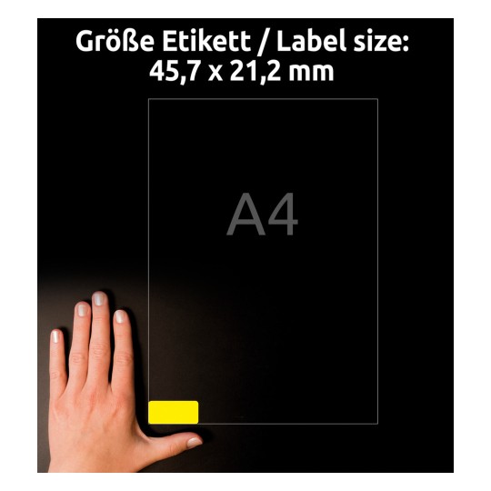 A képen egy kéz látható egy A4-es méretű papír mellett, 45,7 x 21,2 mm méretű címkével, amely egy sárga címkét mutat az alsó sarokban.