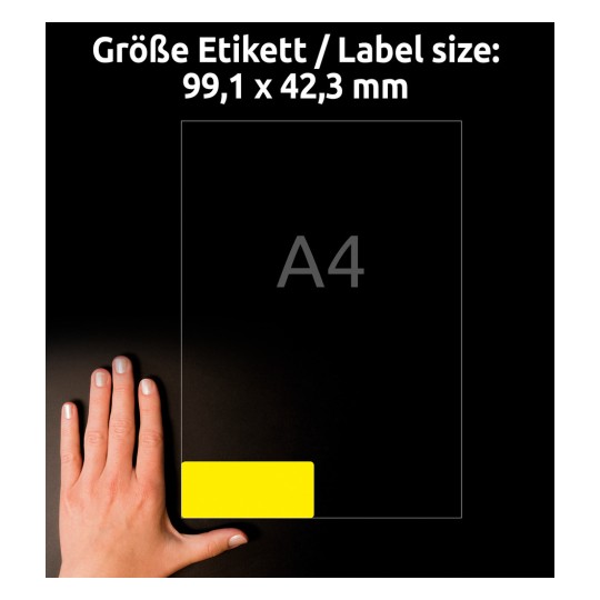 A kép egy 99,1 x 42,3 mm méretű címkét mutat A4-es papírméret mellett, egy kéz pedig a címke elhelyezését demonstrálja.