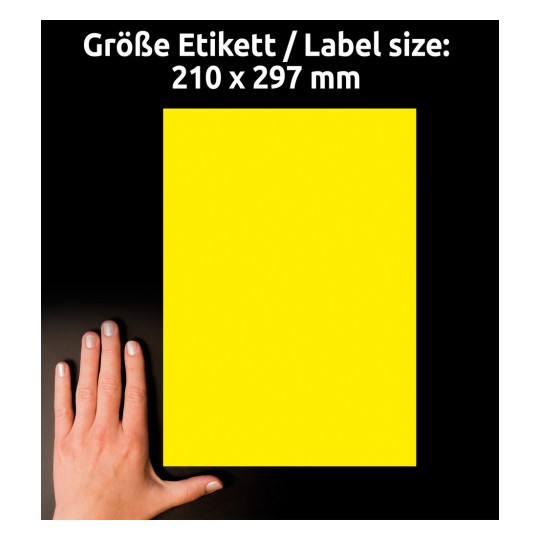 A képen egy élénk sárga címke látható, amelynek méretei 210 x 297 mm, mellette pedig egy kéz nyugszik egy sötét felületen.