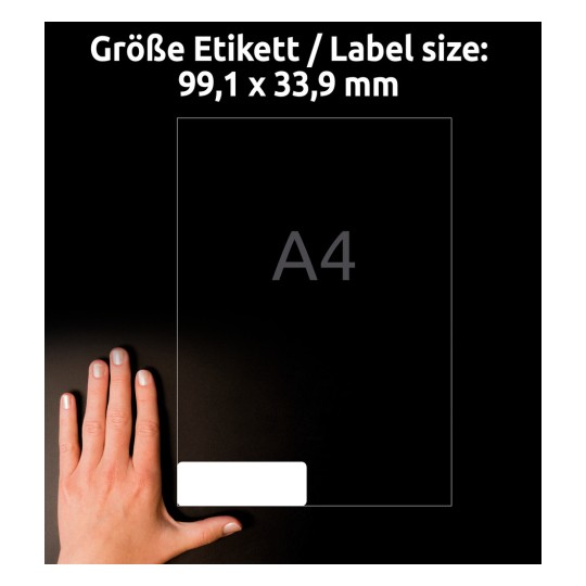 A képen egy kéz látható egy 99,1 x 33,9 mm-es méretű címke mellett, amelyen az A4 méret is említve van. A háttér sötét, és a címke fehérnek tűnik.
