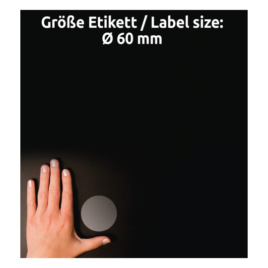 Egy kép, amelyen egy kéz látható egy kör alakú címke mellett, amelynek átmérője 60 mm, sötét háttér előtt. A címke szürke, és a szöveg németül és angolul jelzi a méretét.