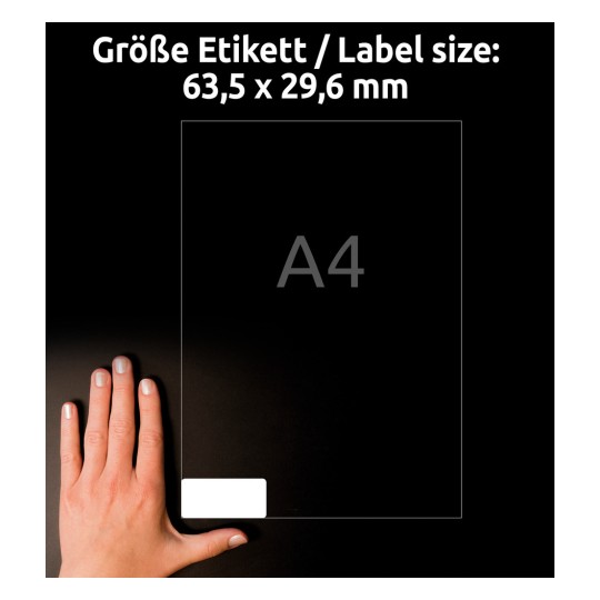 A képen egy kéz látható egy üres címke mellett, amely 63,5 x 29,6 mm méretű, a szöveg szerint A4-es méretű.
