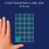 A képen egy kéz látható, amely egy kör alakú címkéket tartalmazó lap mellett van elhelyezve, amelyek mindegyike 18 mm átmérőjű, és egy címke zölddel van kiemelve.