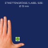 A kép egy kéz látható egy kis zöld mosolygós arcú matrica mellett, a szöveg szerint a matrica mérete Ø 19 mm kék háttéren.