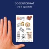A képen látható egy kéz, amely egy matricalapot tart különböző színes mintákkal és családhoz, szórakozáshoz, valamint ételekhez kapcsolódó kifejezésekkel. A lapon olyan idézetek szerepelnek, mint például 'Családi idő' és 'Mosás ma vagy soha.'