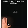 A kép egy kezet mutat, amely egy A4 méretű átlátszó anyagot tart. Egy címke látható rajta, amely egy 10 mm átmérőjű címke méretét jelzi. A háttér sötét.