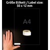 A képen egy kéz látható, amely egy A4-es méretű papírlapot tart egy 50 x 12 mm-es méretű öntapadós címkékből álló tekercs mellett. A háttér sötét, kiemelve a jelenlévő tárgyakat.