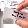 A kép egy kézben tartott névtáblát ábrázol, amelyen az „Avery Paul Meyer” felirat látható. Kiemeli a tábla leválasztásának egyszerűségét, hangsúlyozva a sima széleket.