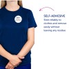 A képen egy személy látható, aki sötétkék pólót visel, rajta egy önragasztó névtáblával, amelyen a következő felirat olvasható: 'B. Carlos MARKETING IGAZGATÓ'. A jobb oldali szöveg az önragasztó jellemzőt emeli ki, hangsúlyozva annak megbízhatóságát és maradványmentes eltávolítását.