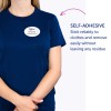 A képen egy személy látható, aki kék inget visel és egy öntapadós névtábla van rajta, amelyen a következő olvasható: 'B. Carlos, marketingigazgató.' A szöveg kiemeli a névtábla ragasztós tulajdonságát, ami azt jelzi, hogy megbízhatóan tapad és maradvány nélkül eltávolítható.