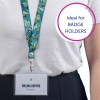 A képen egy személy látható, aki egy színes, trópusi mintájú nyakpántot visel. Egy kitűző van rögzítve, amelyen a 'Melina Doppler' név és a 'Designer' cím szerepel. A háttérben kör alakú szöveg látható: 'Ideális JELVÉNYTARTÓKHOZ.'