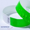 A kép két karkötőt ábrázol; az egyik élénkzöld, rajta vízcseppekkel, míg a másik fehér, texturált mintával. A karkötők mellett megjelenik a 'WATERPROOF' szó, ami arra utal, hogy a zöld karkötő vízálló képességgel bír.
