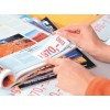 A close-up of a person's hand flipping through a colorful magazine, showcasing an image of a red landscape and a price tag marked €970.