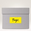 The image shows a grey storage box with a yellow label that says 'Toys'.