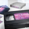 The image features a VHS tape labeled 'beEvents Sales Meeting 2014,' alongside several other media formats, including what appears to be a disk and another VHS tape, all arranged on a white background.