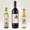 A képen három üveg látható: egy üveg alma balzsamecet, egy 'Night Owl' címkéjű vörösboros üveg és egy tejszínes likőrös üveg. Világos háttéren vannak elrendezve.