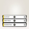 A képen három dosszié látható egymásra rakva. A felső dosszié felirata 'BUDGET', a középsőé 'MEETINGS', az alsóé 'MARKETING'. Egyszerű kialakításúak, fekete széllel és fehér előlappal rendelkeznek.