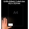 A kép egy kézben tartott 63,5 x 33,9 mm méretű címkelapot ábrázol, háttérben A4-es méretű papírral. A címkén van egy üres terület a testreszabáshoz.