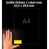 A kép egy kéz látható, amely egy mérettáblázat közelében helyezkedik el, amely 63,5 x 29,6 mm-es méreteket mutat 'A4' megjelöléssel. A háttér sötét, kiemelve a címke és a szöveg láthatóságát.