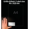 A kép egy kezet mutat egy címke mellett, amely a címke méretét 96 x 50,8 mm-ként jelöli, A4-es méretekkel, sötét háttéren.