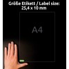 A képen egy kéz látható, amely egy címkeméret-jelző mellett van elhelyezve, amely 25,4 x 10 mm-es méreteket mutat, a háttérben pedig egy A4-es papírlap található.