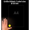 A kép egy kézfejet ábrázol egy A4 méretű papír mellett. Az papír alsó sarkában egy kör alakú, 30 mm átmérőjű sárga címke található. A háttér sötét, ami fokozza a láthatóságot.