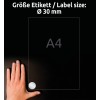 A kép egy kezet ábrázol, amelyet egy sötét felületre helyeztek egy A4-es lap mellé, amelyen egy 30 mm-es kör alakú címke található.
