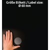 Egy kép, amelyen egy kéz látható egy kör alakú címke mellett, amelynek átmérője 60 mm, sötét háttér előtt. A címke szürke, és a szöveg németül és angolul jelzi a méretét.