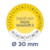 A képen egy kör alakú mérőműszer látható, amelyen számok jelölik a méréseket, és kiemelten szerepel a 'Geprüft nach DGUV Vorschrift 3' és 'Ø 30 mm'.